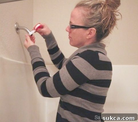 Wrapping Shower Arm with Teflon Tape Applying Teflon tape clockwise around the threads of the shower arm.