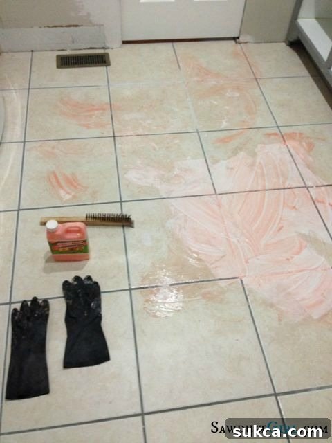 Applying orange paint stripper to tile and grout for effective paint removal