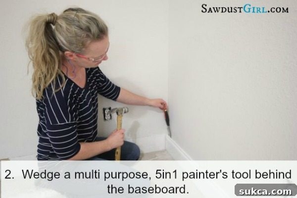 Carefully using a 5-in-1 painter's tool to wedge behind the baseboard and create a small initial gap.
