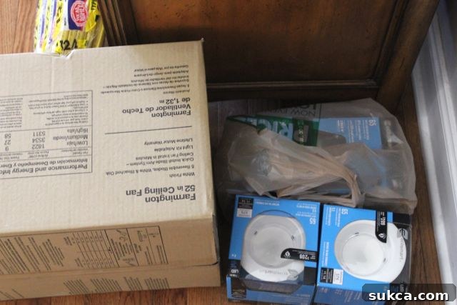 Brand new ceiling fan and recessed can lights still in their unopened boxes, awaiting installation in a home office