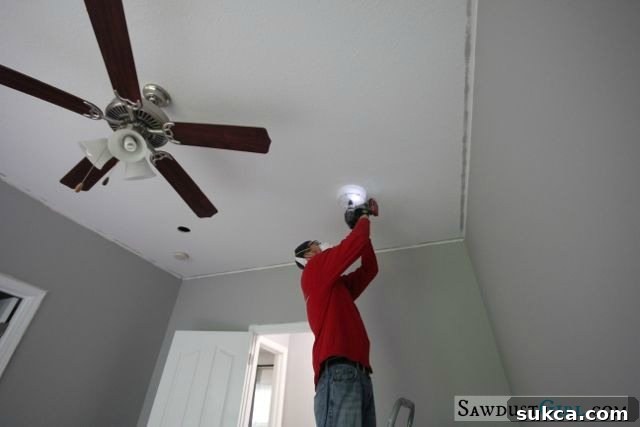 Wes installing new recessed lights in the office ceiling. He is on a ladder, carefully working on the electrical wiring for the modern LED fixtures.