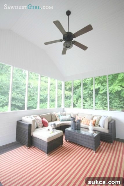 Elegant screened-in porch with cozy furniture, perfect for relaxing and enjoying the outdoors bug-free in a renovated home.