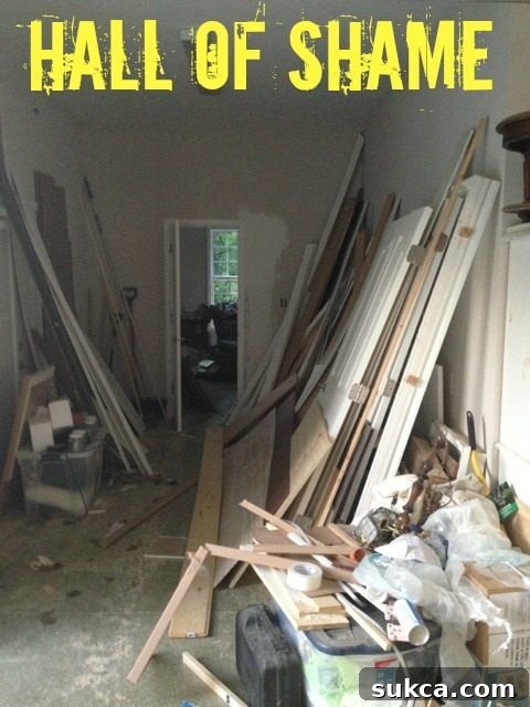 The Hall of Shame A cluttered hallway between garages, packed with wood scraps and stored items, earning the title 'hall of shame'.