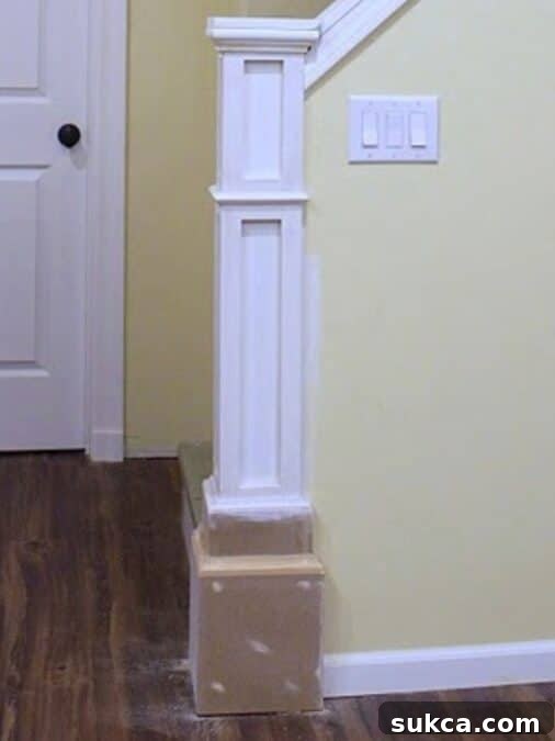 Partially built newel post with primed trim and stacked MDF base before painting