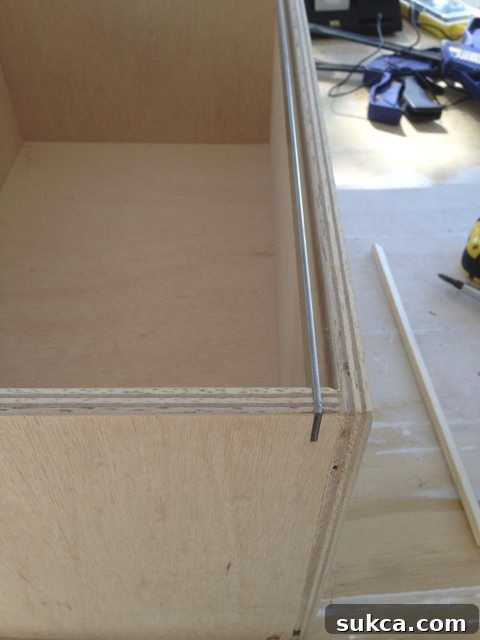 Checking the fit of a metal hanging file bar within a freshly cut groove in the drawer.