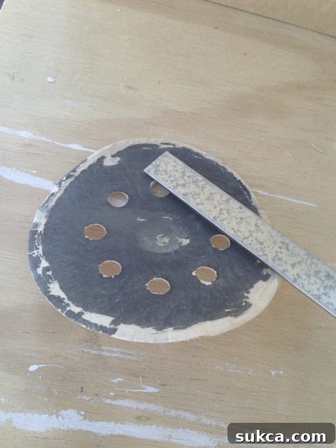 A hand smoothing the cut edge of a metal hanging file bar with sandpaper.