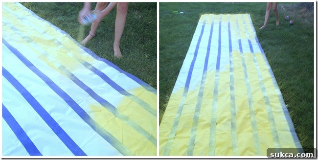 Sophie painting stripes A child (Sophie) happily spray painting an outdoor fabric lemonade stand canopy, demonstrating the ease and fun of the DIY project.