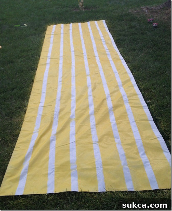 Spray painted canvas fabric Close-up of the freshly spray-painted striped canvas tarp after tape removal, showing crisp lines and the vibrant yellow color, ready for the lemonade stand.