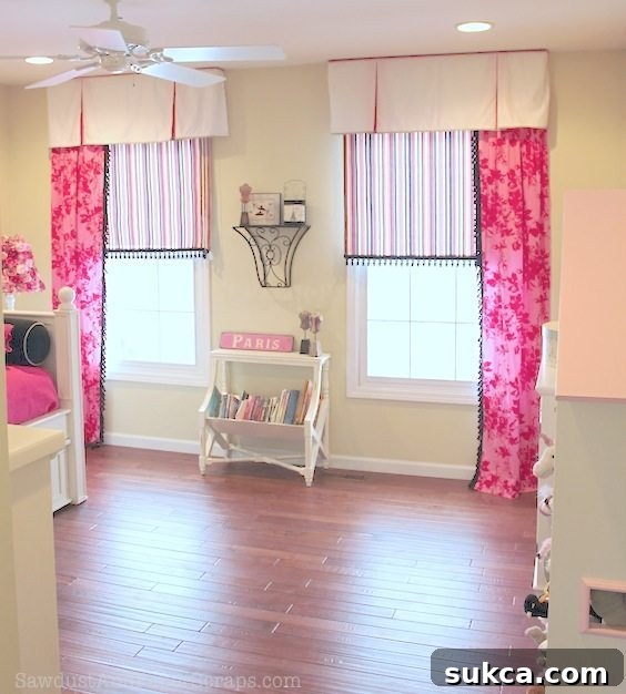 Close-up of girl's bedroom window treatment featuring custom roller shades, drapes, and DIY valances made from a repurposed bedskirt.