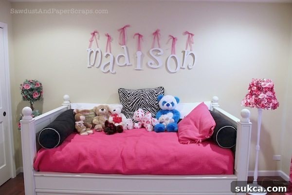 Girl's bedroom featuring a stylish bed, personalized wall letters, and custom decor, emphasizing a pink and zebra theme.