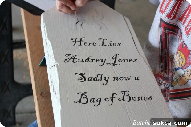 Close-up of a DIY tombstone with painted spooky sayings, showing the detail work.
