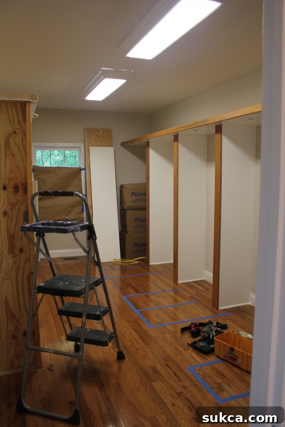A dimly lit, disorganized master closet before renovation with poor quality plywood structures.