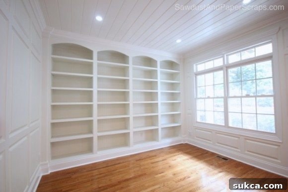 Custom white built-in library shelves with wainscoting detail in a newly renovated living room.