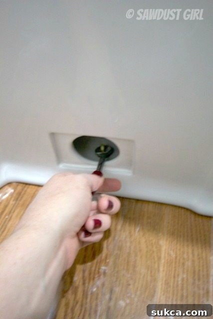 Securing a one-piece skirted toilet to flange Securing the base of a skirted toilet to the floor flange with nuts and washers.
