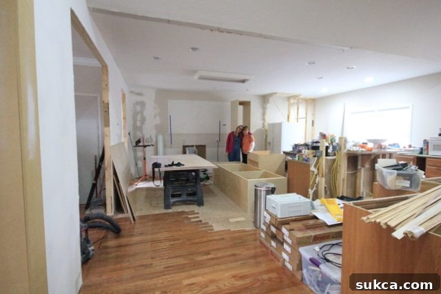 Two people working together to build custom kitchen cabinets for the oven, cooktop, and a broom closet.