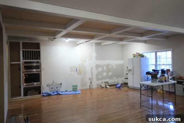 Kitchen space with new flooring, partially installed box beam ceiling, and some custom cabinets in place during renovation.