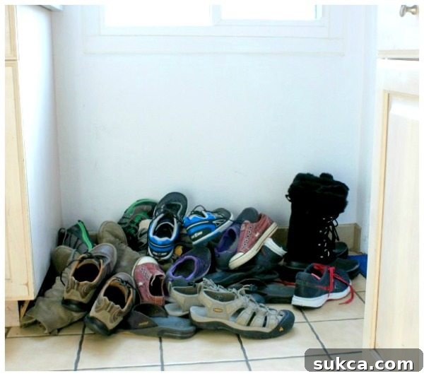 Entryway Before Shoe Peg Storage A cluttered entryway floor before implementing the DIY shoe peg organization. Shoes are piled and scattered, making it difficult to access the boot tray.