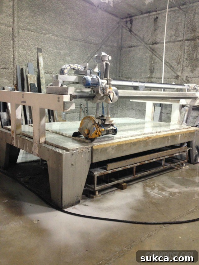 Inside a countertop fabrication shop, showing a large stone slab on a cutting table, emphasizing the industrial process of creating custom countertops.