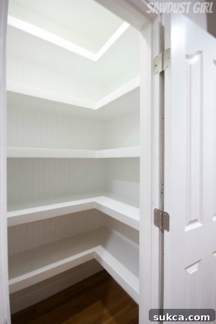 Completed hall closet with white U-shaped floating shelves spanning all three walls