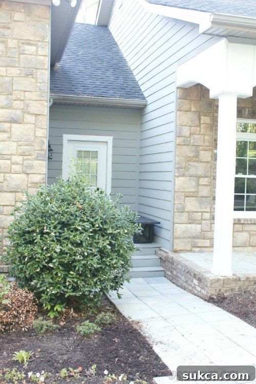 Side entrance with an X-leg bench and discreet recycling bins underneath.