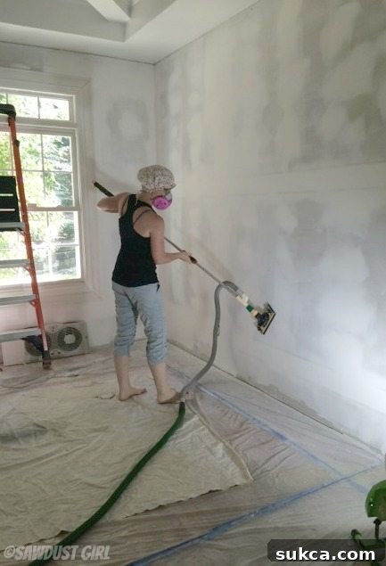 Effective and clean drywall sanding in progress Close-up of a person actively sanding drywall with a dust-free sander