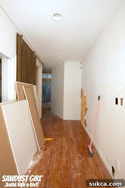 The final stages of drywall patching and mudding are complete, leaving a smooth, prepared surface for the pantry's next phase.