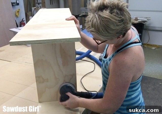 Cabinet panel being sanded smooth after wood filler application, showing a meticulous sanding process.