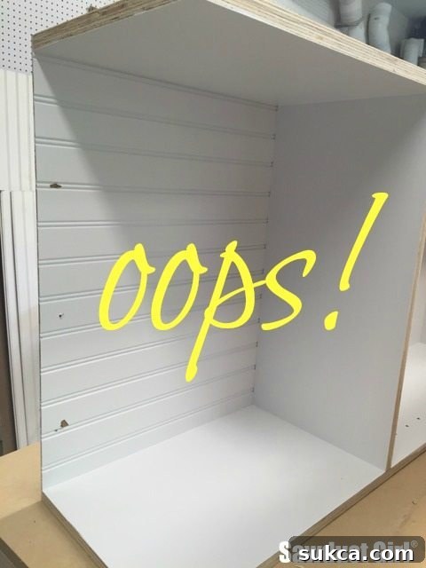 Close-up of the cabinet back nailed, showing a nail inadvertently driven into the temporary spacer, highlighting a common DIY error.