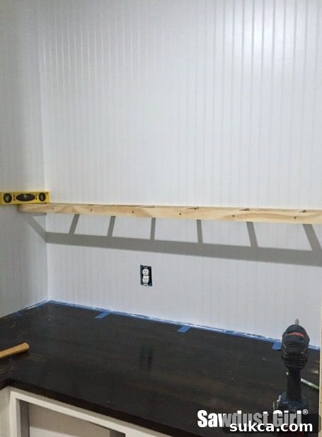 Installing Floating Shelf Ribs Floating shelf ribs securely fastened to the pantry wall studs using long cabinet screws, showing the framework in place.