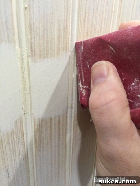 Detail sanding beadboard grooves with a customized tool.