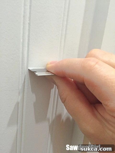 Using a razor blade to flatten bumpy paint finish on beadboard.