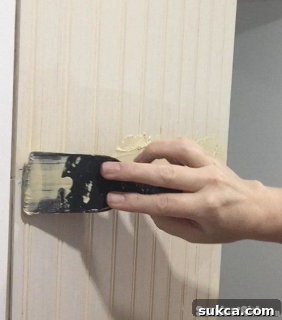Applying wood putty generously to hide beadboard seams.