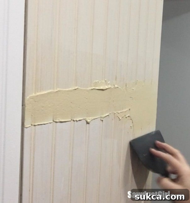 Feathering out wood putty to blend beadboard joints.