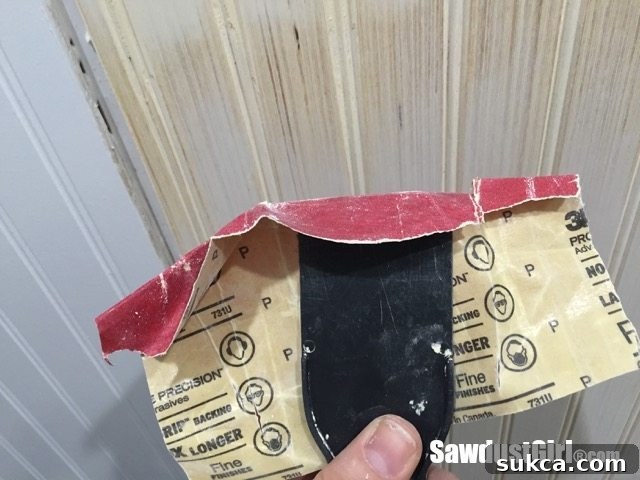 Putty knife wrapped in sandpaper for precise beadboard groove sanding.