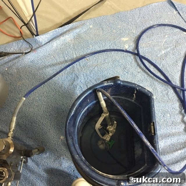 Sprayer Storage Tip Airless paint sprayer stored in a pail of water to prevent paint from drying and clogging, a smart maintenance tip