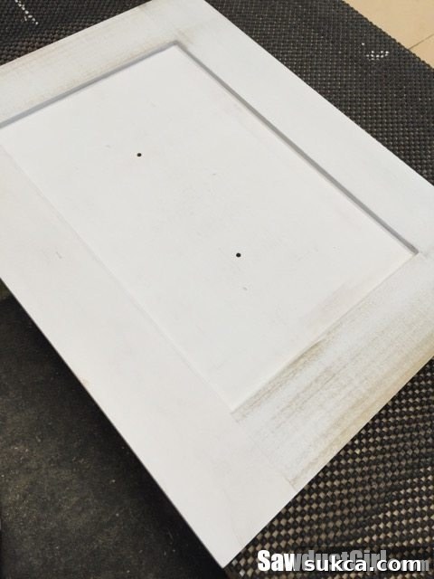 Priming Cabinet Doors First coat of primer applied to a cabinet door, showing areas where a second coat may be needed for even coverage