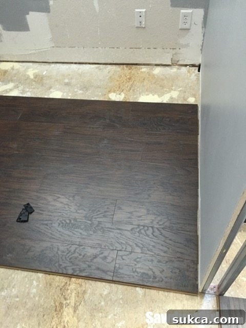Laminate flooring installation meeting a wall with baseboard coverage