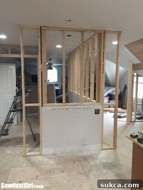 Overview of a loft renovation project, showing a newly framed wall for a powder room, demonstrating smart space utilization in DIY home improvement.