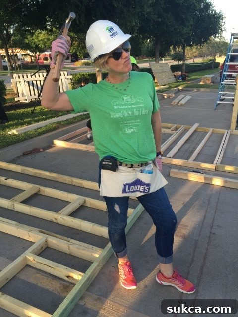 Smiling woman volunteer hammering a nail at the build site