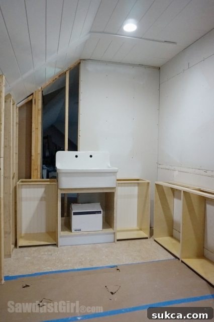 Craft room utility sink placement - Cabinets built for the utility sink area, with plumbing rough-in completed, ready for further installation.