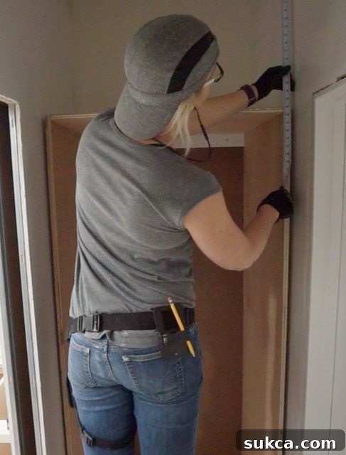 Measuring for the upper wardrobe cabinet, accounting for crown molding and spacers