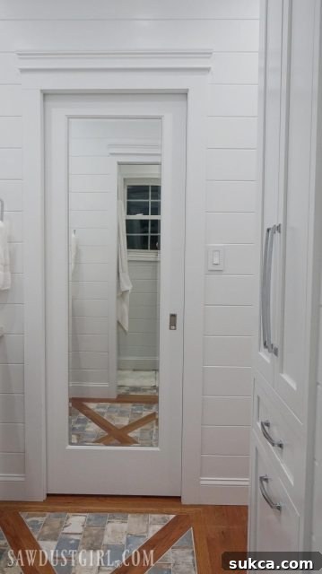 A view of the completed Jack and Jill bathroom, showing the mirrored pocket door and a glimpse of the finished linen closet.