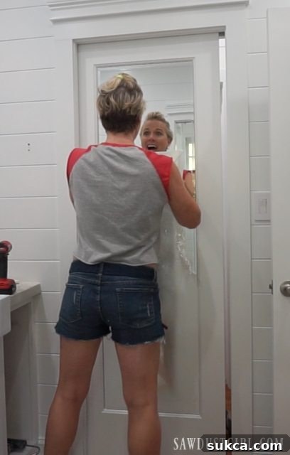 Removing protective plastic from the mirrored door after painting, revealing a clean, reflective surface.