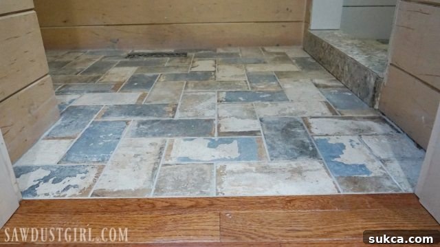 Applying grout to the new tile floor Grouting a flush tile and hardwood floor