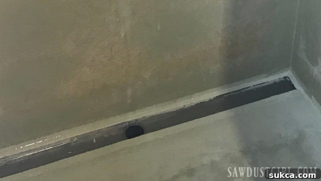 Tile ready shower pan installation: Applying HYDRO BAN waterproofing membrane over the drain flange.