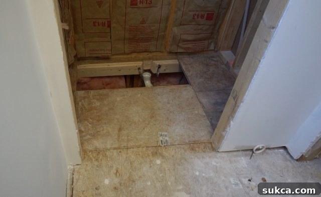 Installing preformed shower pan: Close-up of subfloor preparation and drain rough-in.
