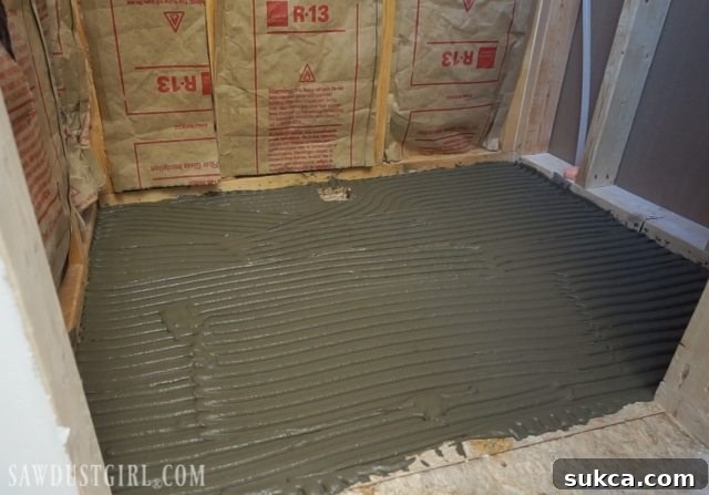 Tile ready shower pan installation: Ensuring full mortar coverage before pan placement.