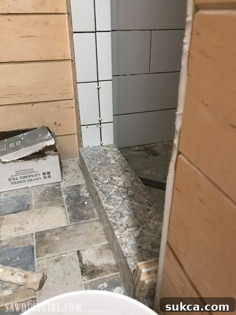 Unsatisfactory Doorway Tiling Attempt Tiling the Shower: An initial attempt at tiling the shower doorway and threshold, showing an undesirable patchy appearance.