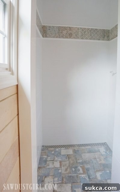 Completed Shower Tiling Project Tiling the Shower: The fully tiled and grouted shower, showcasing the completed aesthetic with large format tiles and decorative elements.