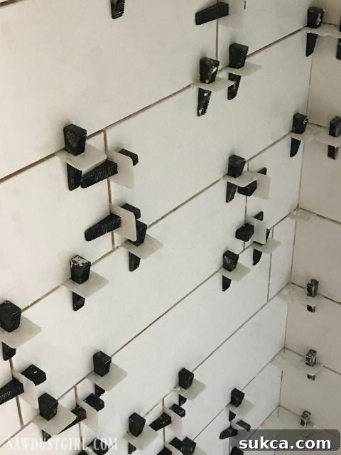 Leveling Spacers Ensuring Perfect Tile Alignment Tiling the Shower: Close-up view of the leveling spacer system in action, ensuring perfectly flat and evenly spaced tiles.